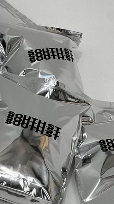 some silver foil bags with black letters on them