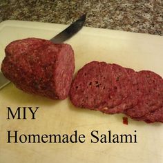 a large piece of meat sitting on top of a cutting board next to a knife