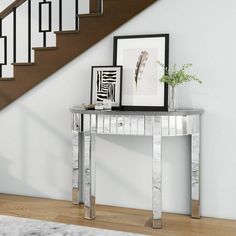 a modern console table in front of a staircase with framed pictures on the wall and a plant next to it