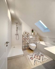 an attic bathroom with a skylight above the toilet and sink area, along with a rug on the floor