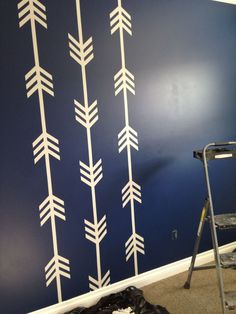 the wall is painted with white arrows on blue and has a ladder in front of it