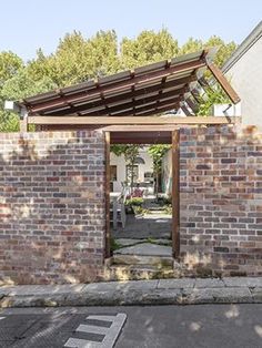 a brick building with an open door on the side and trees in the back ground