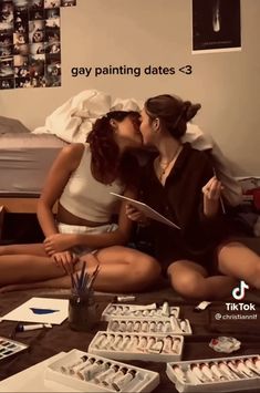 two women sitting on the floor kissing each other