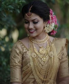 a woman in a gold sari with flowers on her head and necklaces around her neck