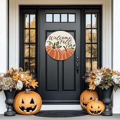 two pumpkins sitting in front of a black door with welcome fall written on it