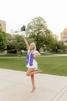 a young woman is jumping in the air with her graduation cap on and she is wearing a purple vest