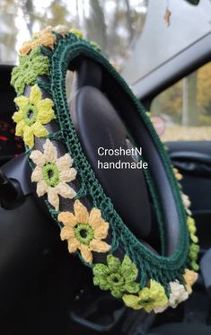 the steering wheel cover is decorated with crochet flowers and green trimmings