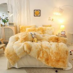 a teddy bear sitting on top of a bed covered in fluffy yellow blankets and pillows