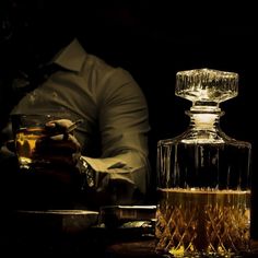 a man sitting at a table next to a bottle of alcohol and a glass with something in it