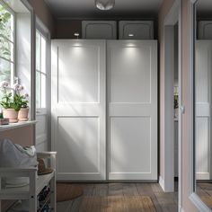 an empty hallway with white closet doors and potted plants in the window sill