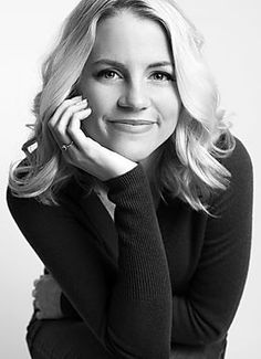 a black and white photo of a woman with her hand on her chin looking at the camera