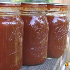 four jars filled with brown liquid sitting on top of a wooden table