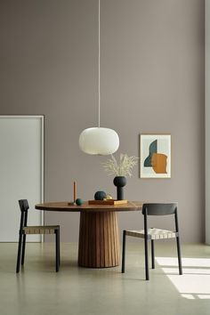 a dining room table with two chairs and a lamp hanging from it's ceiling