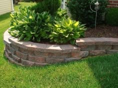 a brick planter in the middle of a lawn