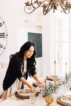 a woman is setting the table for dinner