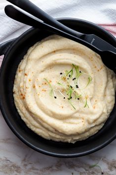 a black bowl filled with mashed potatoes and garnished with herbs on top