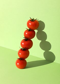 three tomatoes are arranged in the shape of a spiral on a green surface with shadows