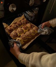 a person pulling out some food from an oven