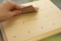 a person using a piece of wood to cut holes