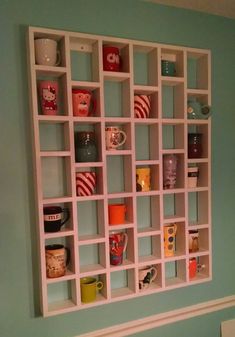 a wall mounted shelf with cups and mugs on it in a room that has blue walls