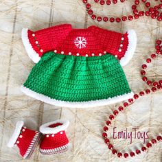 a crocheted christmas outfit and booties on a table next to red beads