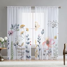 the curtains are decorated with colorful flowers and leaves on them, along with a chair