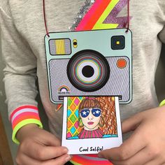 a person holding up a polaroid camera with the image of a woman's face on it