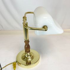 a white and gold desk lamp sitting on top of a table next to a wire