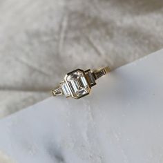 an engagement ring with three baguettes on top, sitting on a piece of paper