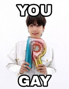 a woman holding up a giant letter in front of her face with the words you gay on it