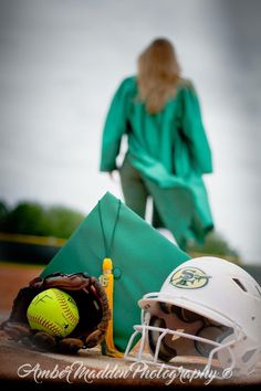 a softball helmet, glove and ball on a baseball field with a woman in the background