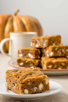 a stack of pumpkin bars sitting on top of a white plate next to a cup