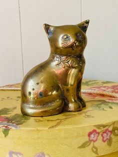 a gold colored cat statue sitting on top of a floral tablecloth covered table cloth