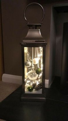 a lantern is lit up with christmas lights and ornaments in it's glass case