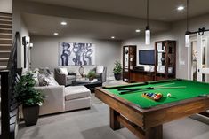 a living room with a pool table, couches and a flat screen tv on the wall