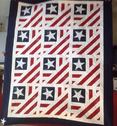 someone holding up a quilt with stars and stripes in the center, on top of a red white and blue blanket