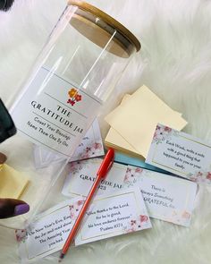 a person holding a pen near some cards and a jar on a white furnishing