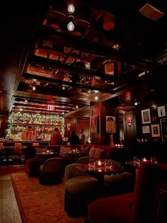 a dimly lit bar with lots of seating and candles on the tables in front of it