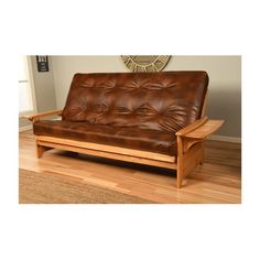 a brown leather futon bed sitting on top of a hard wood floor next to a window