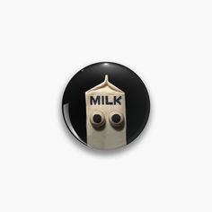 a button with the words milk on it and two eyes in front of an object