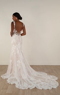 a woman in a white wedding dress standing on a wooden floor with her back to the camera