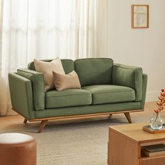 a living room with a green couch and coffee table in front of the window,