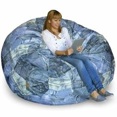 a woman is sitting on a bean bag chair with her legs crossed and holding a tablet