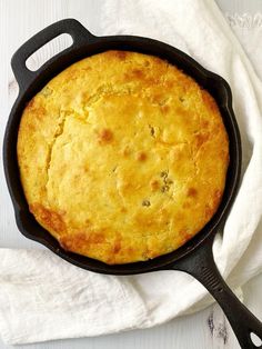 a skillet with some food in it on top of a white cloth and napkin