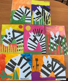 four zebras are painted on different colored paper squares and placed on a wooden table