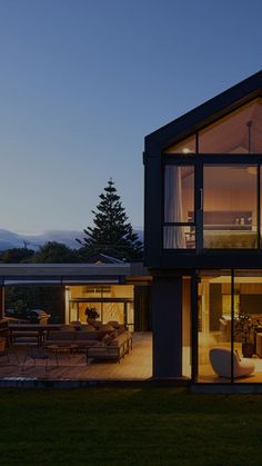 a modern house lit up at night with large windows on the front and back walls