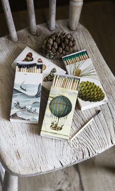 four cards sitting on top of a wooden chair next to pine cones and other items