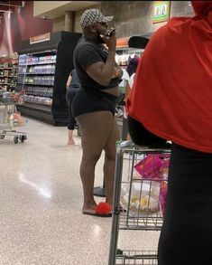 a woman standing in a grocery store talking on her cell phone while holding a shopping cart