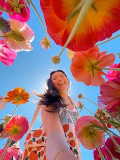 a woman is standing among flowers and smiling