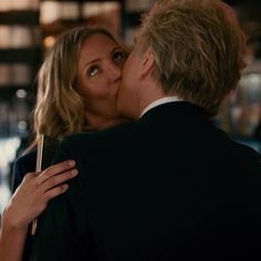 a man and woman kissing each other while standing in front of a bar with lights on